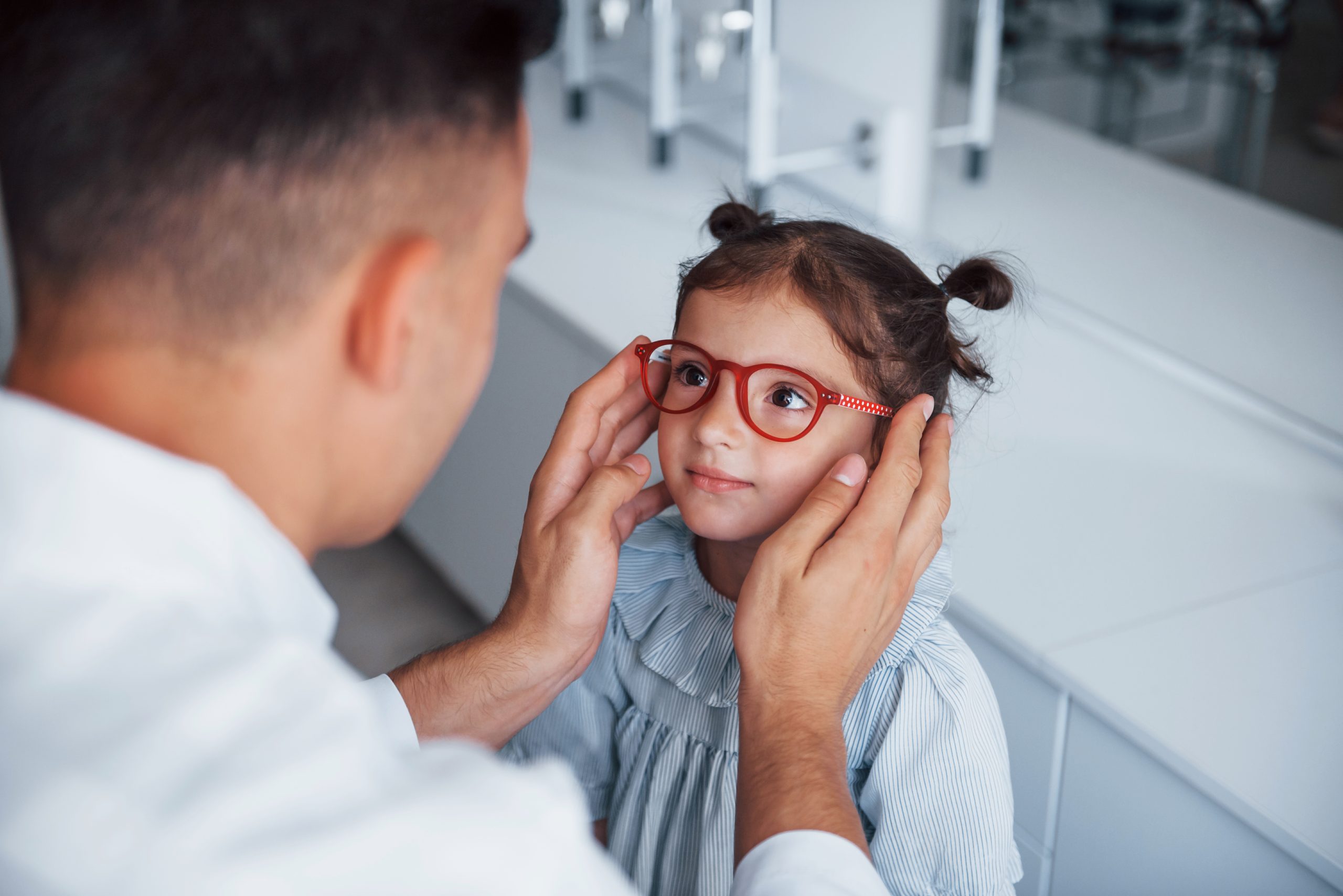 a little girl trying on a pair of red glasses