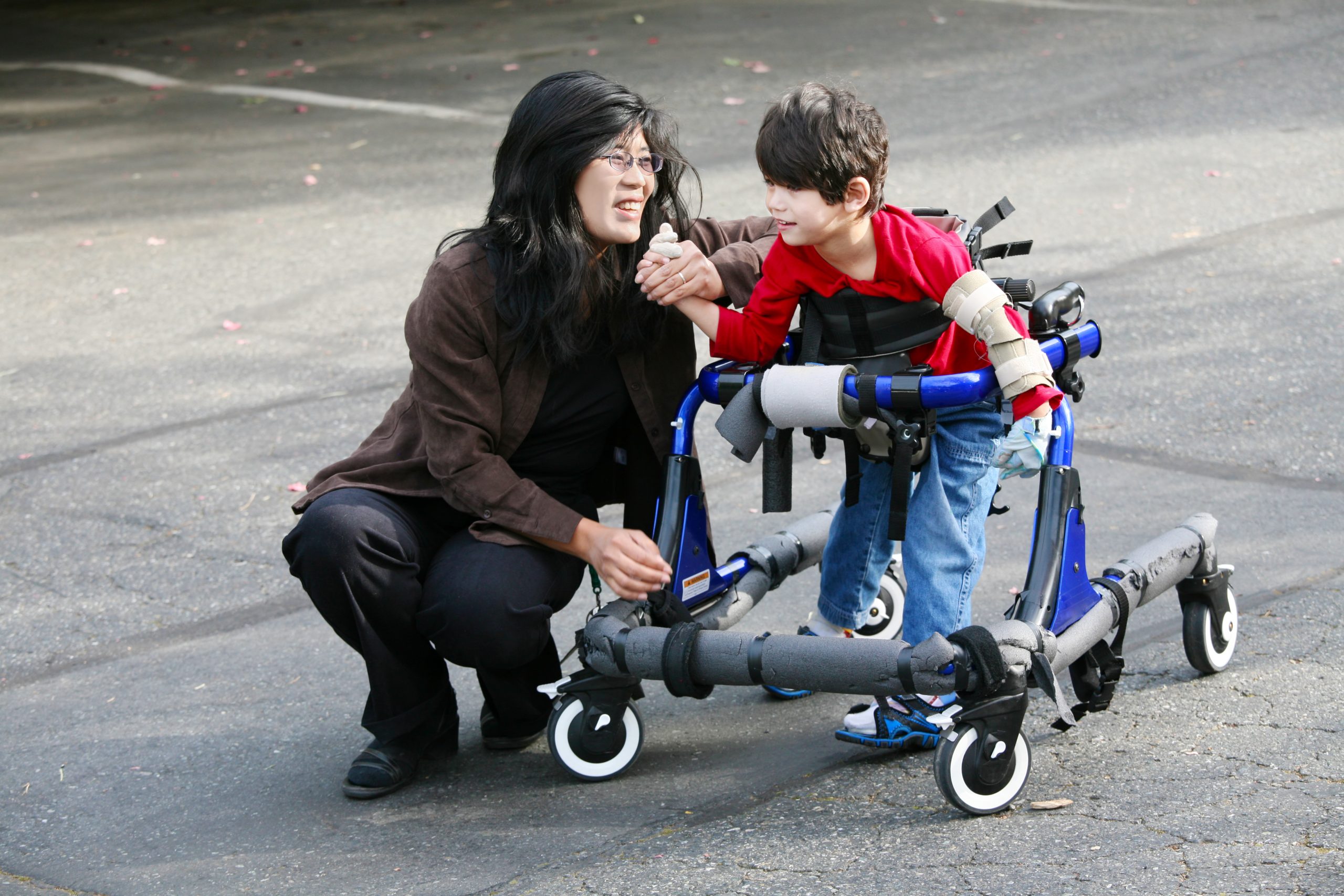 a young boy using a walking wheelchair